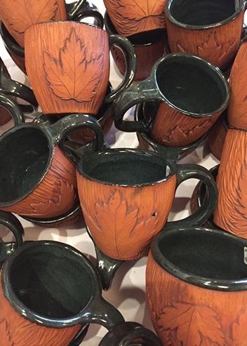 many different sizes and shapes of mugs with leaf design