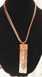 three strand necklace with long rectangular copper piece with clay beads.