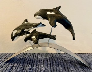 3 different size paper clay orca whales on metal